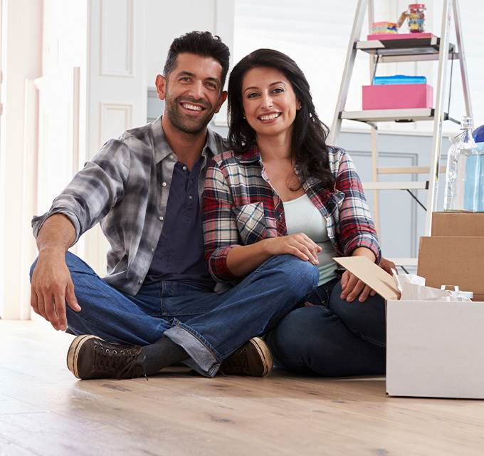 A couple sitting on the floor of a new home